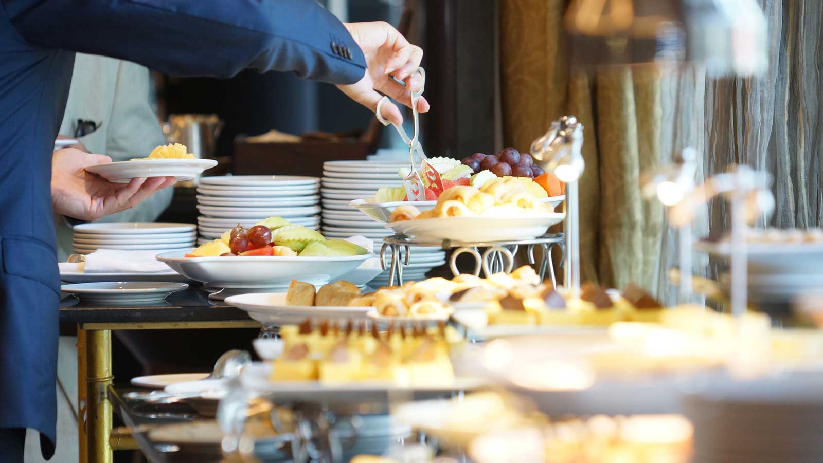 Hotel guest putting food on his plate from the complimentary hot breakfast bar